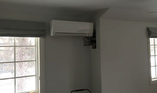 A room with two windows and a wall-mounted air conditioner.