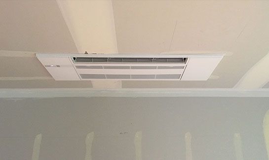 A white air conditioner is hanging from the ceiling of a room.