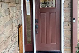 The front door of a house with a stone wall and a brown door.