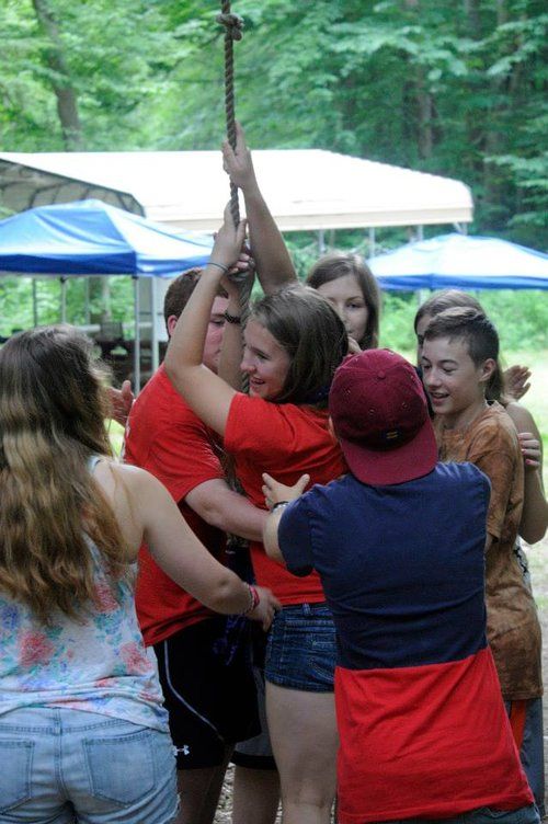 A group of people are standing in a circle holding a stick.