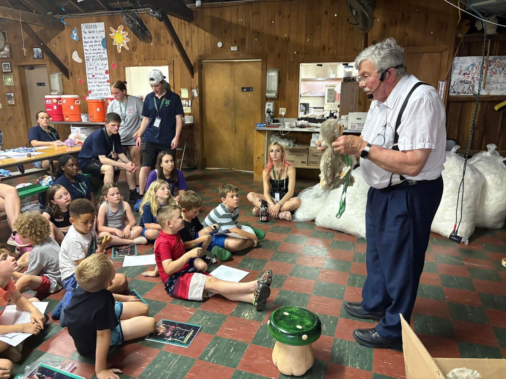 A man is giving a presentation to a group of children sitting on the floor.