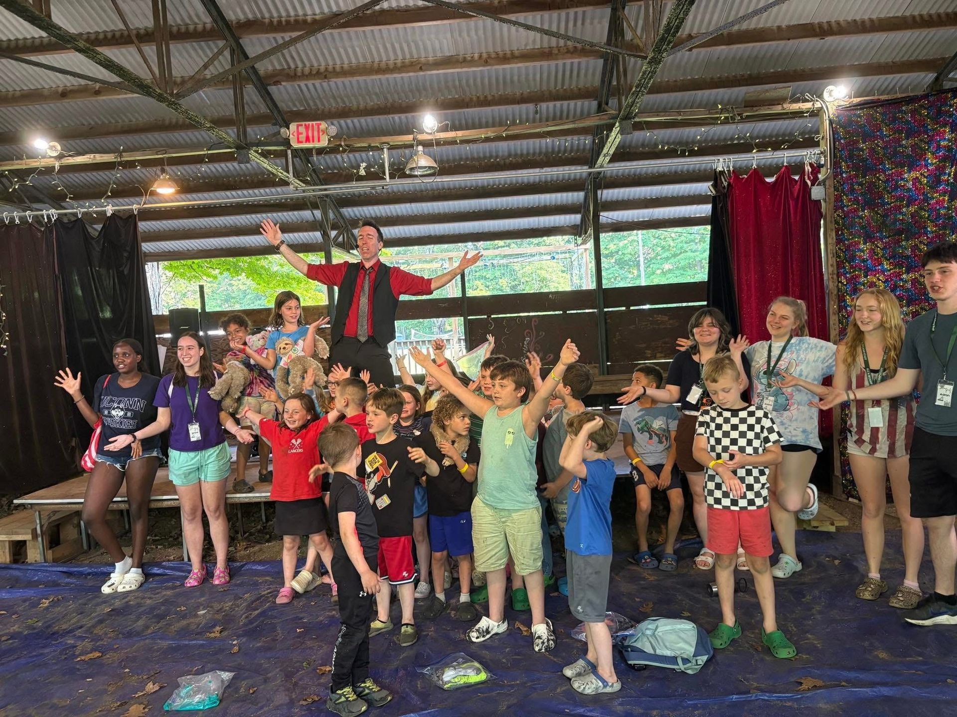 A group of children are standing in a room with their arms in the air.
