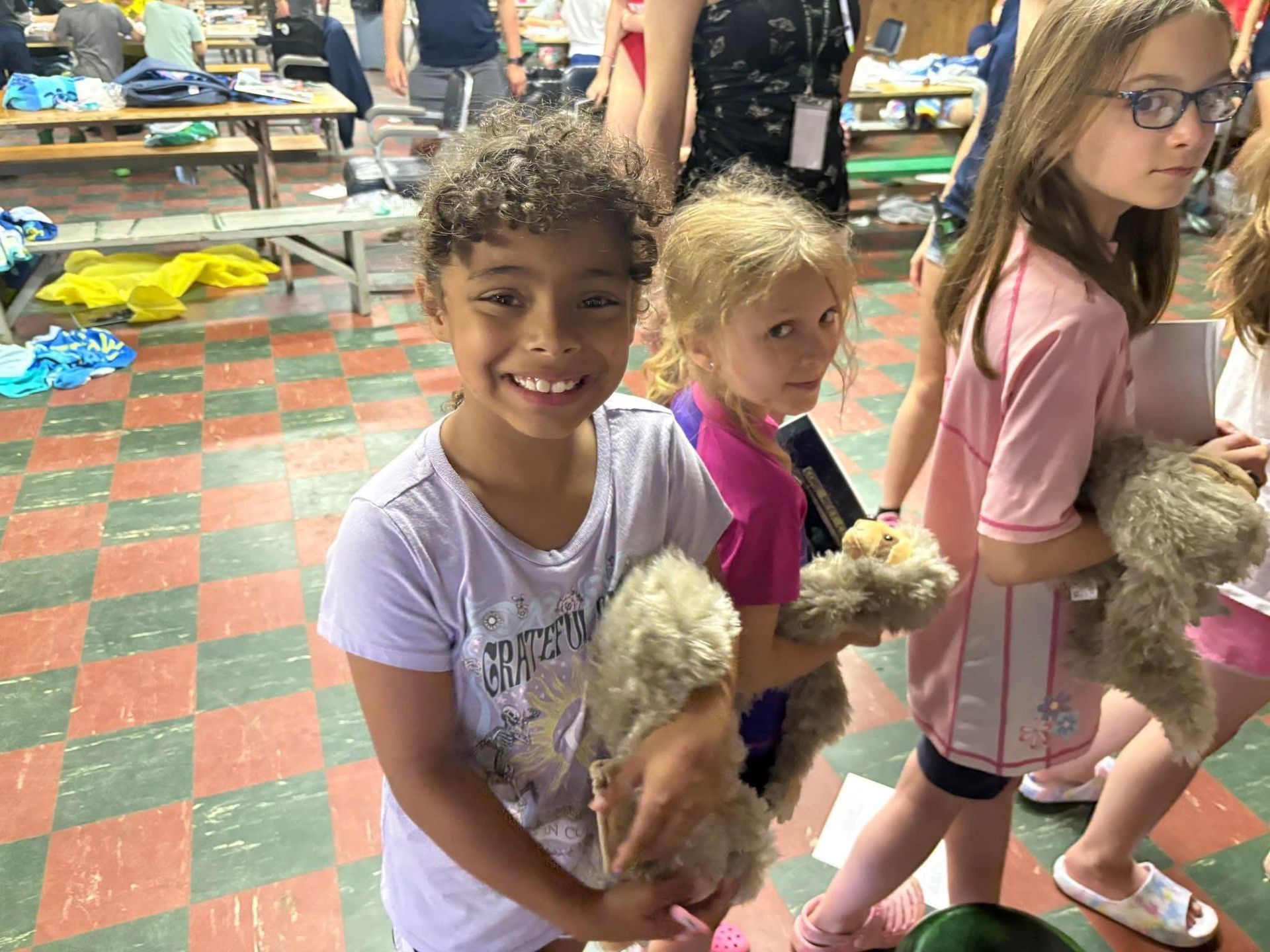A group of young girls are holding teddy bears in a room.