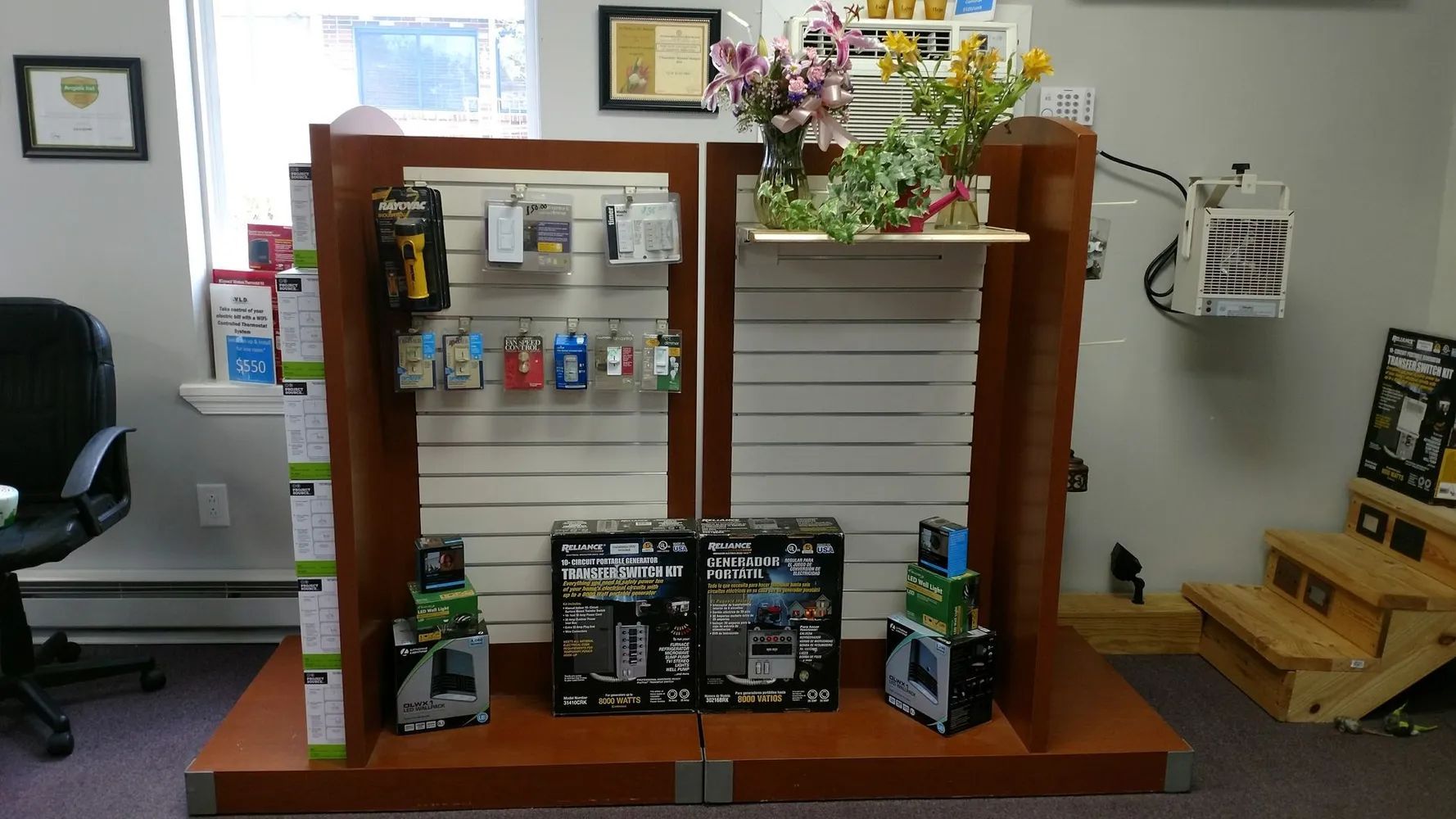 Display of various products on a wooden retail display with shelves. Products include tools, electronic devices, and plants.