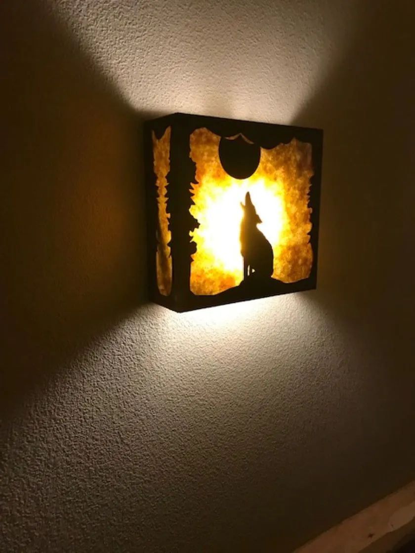 Wolf silhouette lamp glowing on wall, casting light.