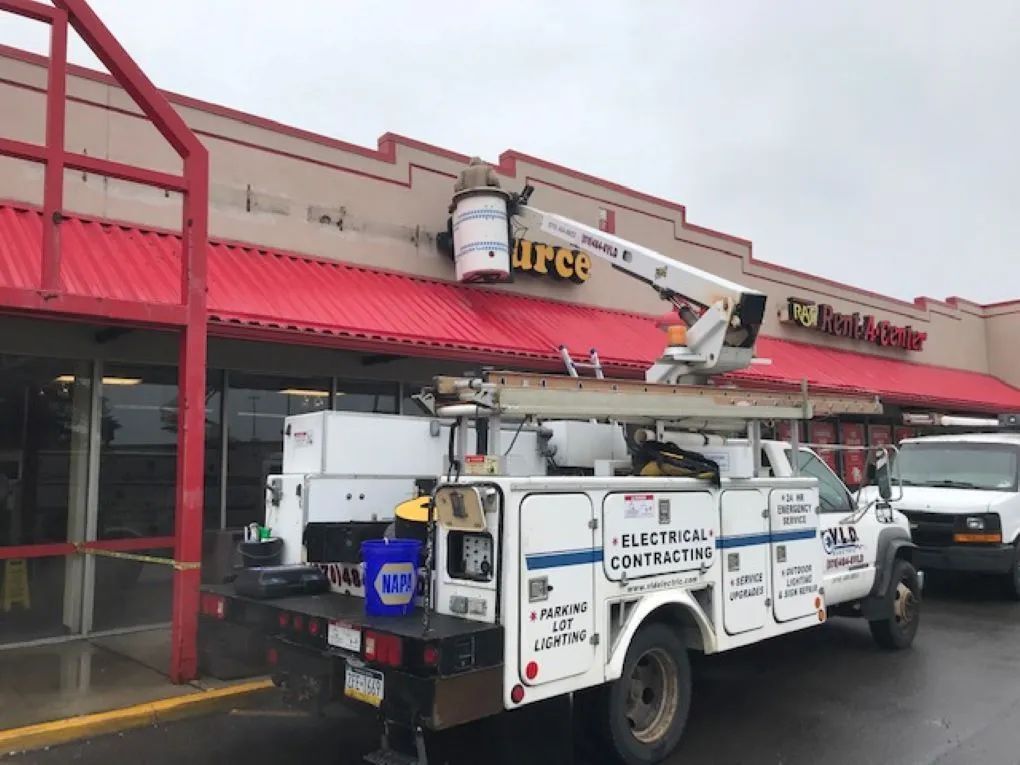 Electrical contractor truck with a lift servicing a store sign.