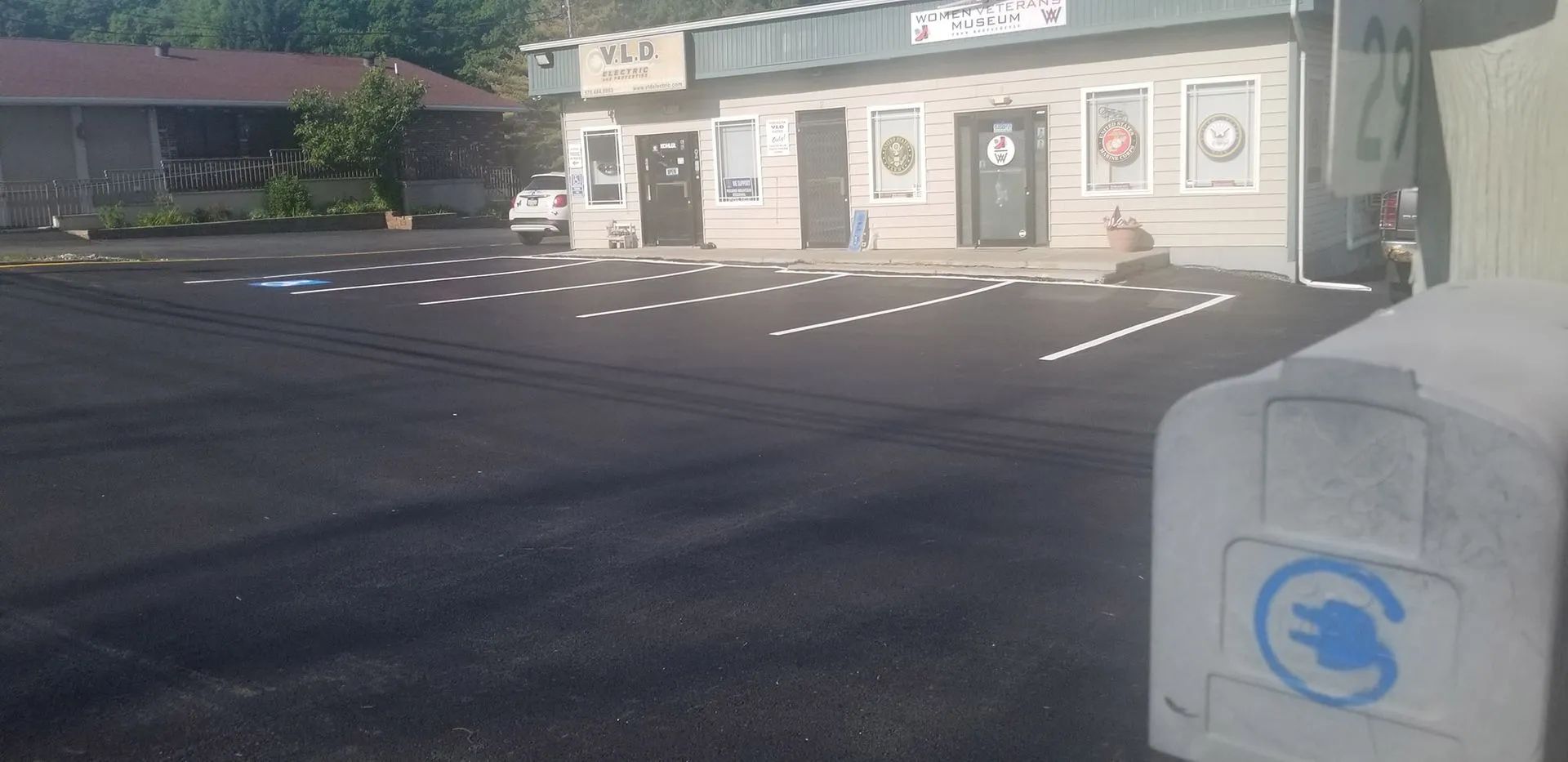 Exterior of a business with a parking lot. An electric vehicle charging station is in the foreground.