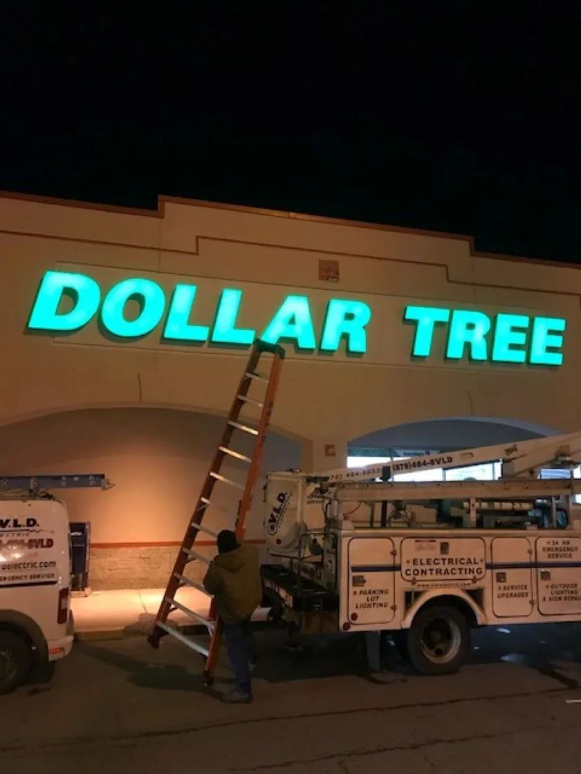 Man on ladder working on a lit-up 
