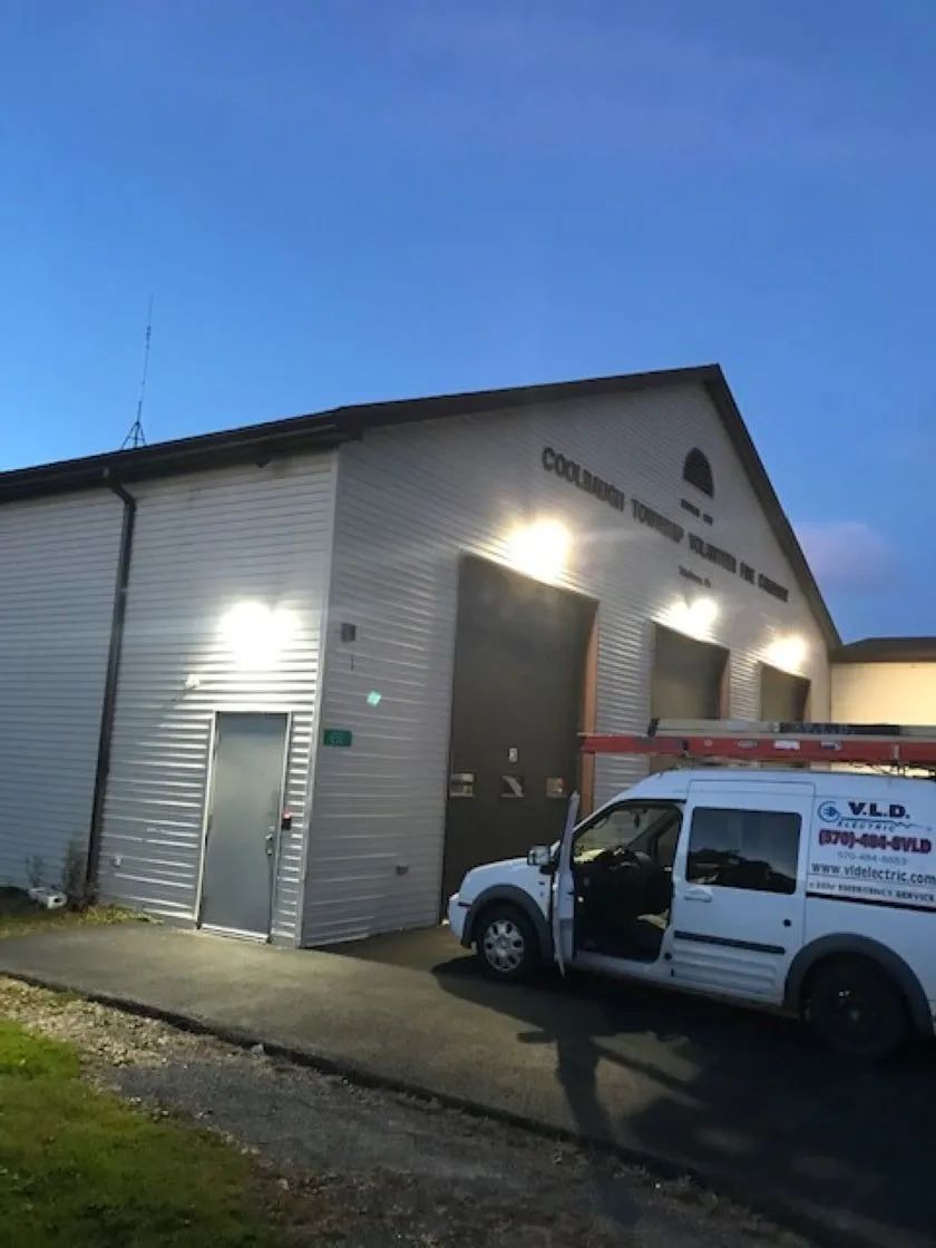 White building with large garage doors, parked van with open door. 