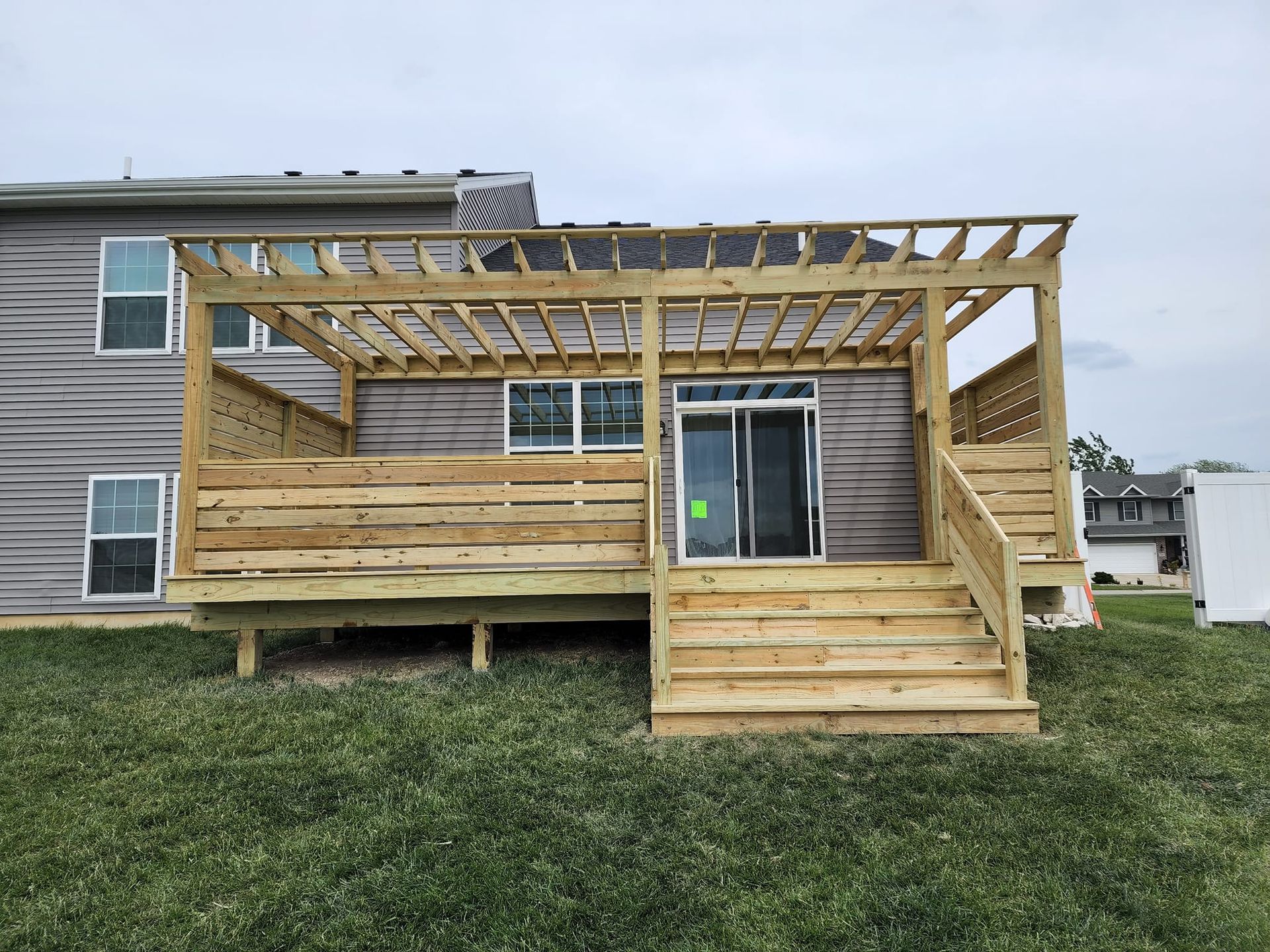 The back of a house with a wooden deck and pergola.