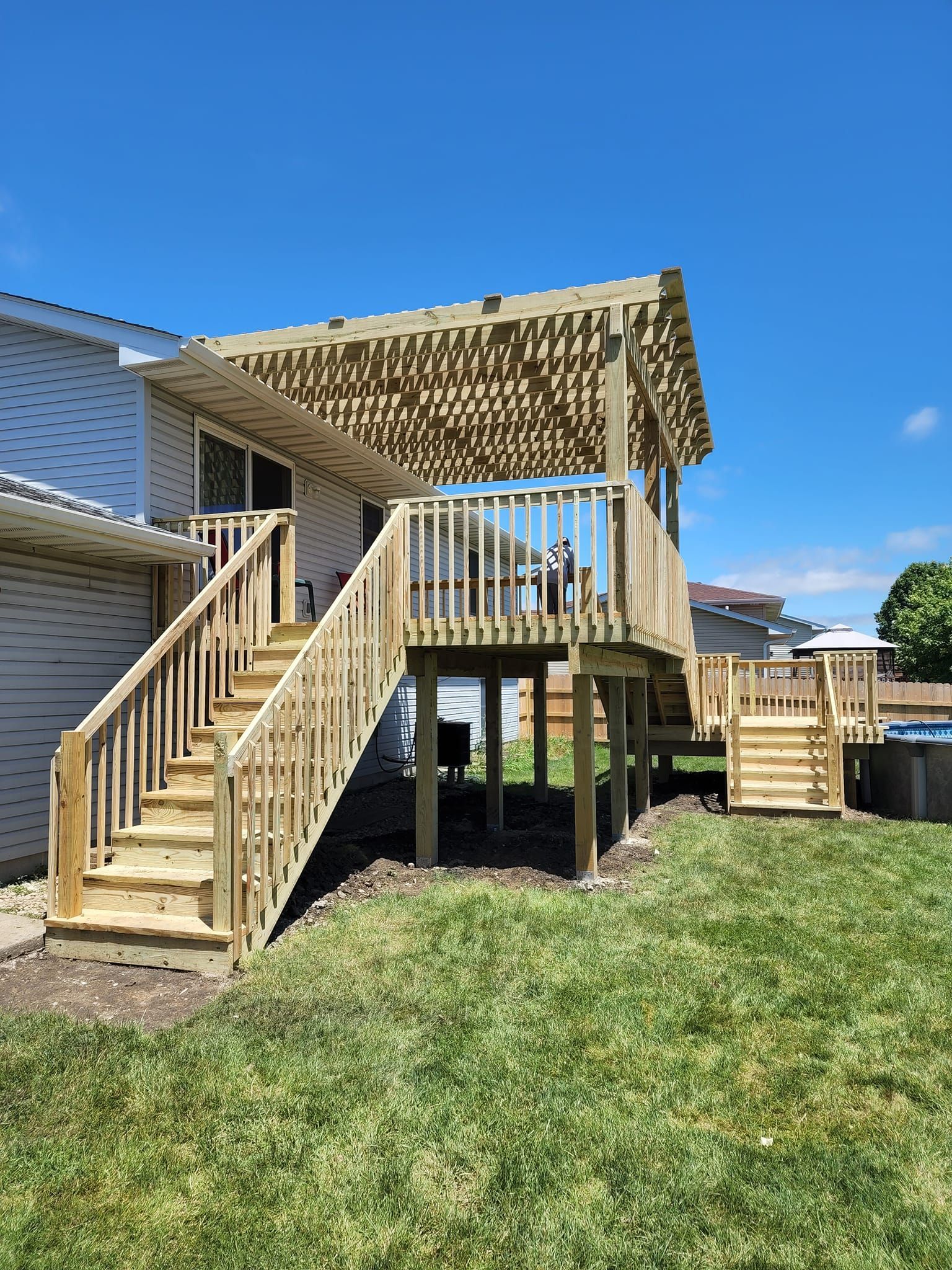 A wooden deck with stairs and a canopy in the backyard of a house.