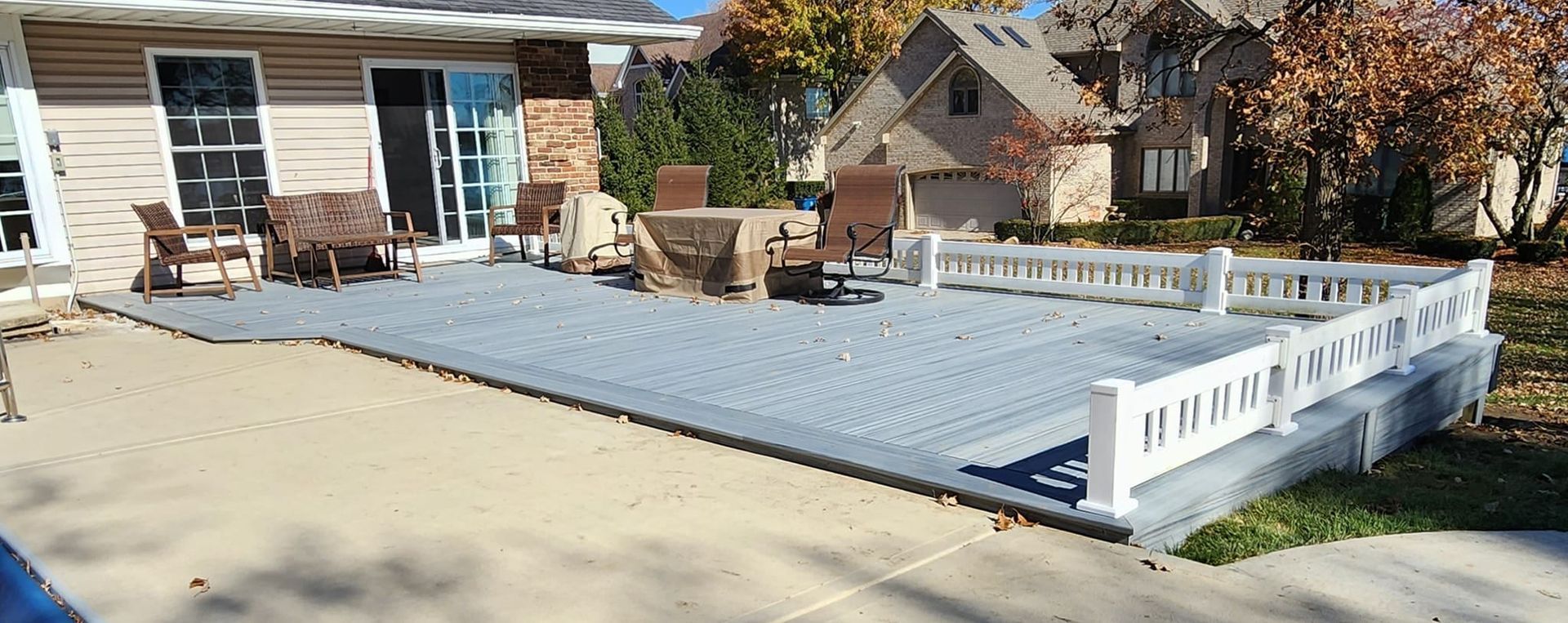 A large patio with a white fence in front of a house.