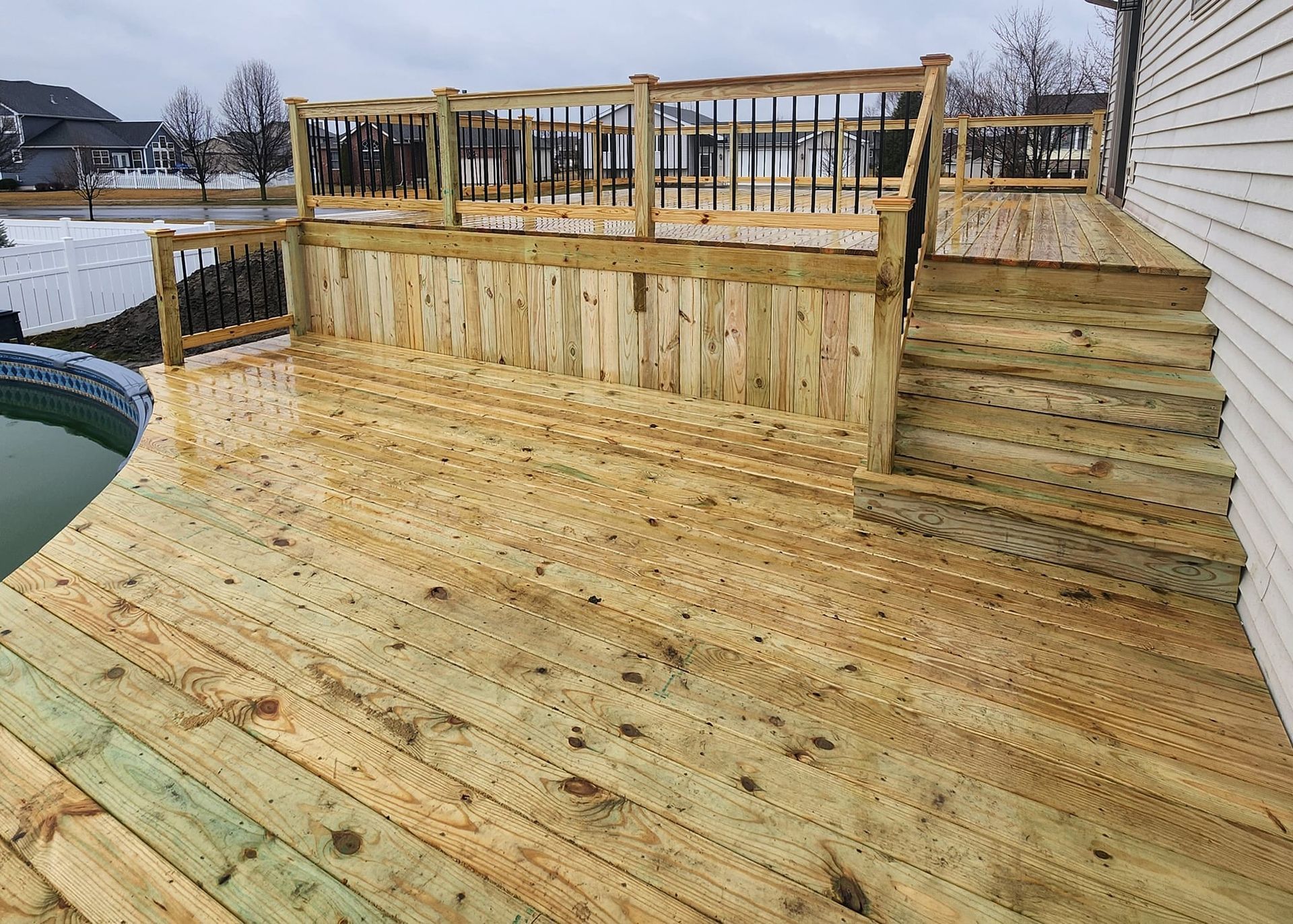 A wooden deck with stairs leading up to it next to a pool.