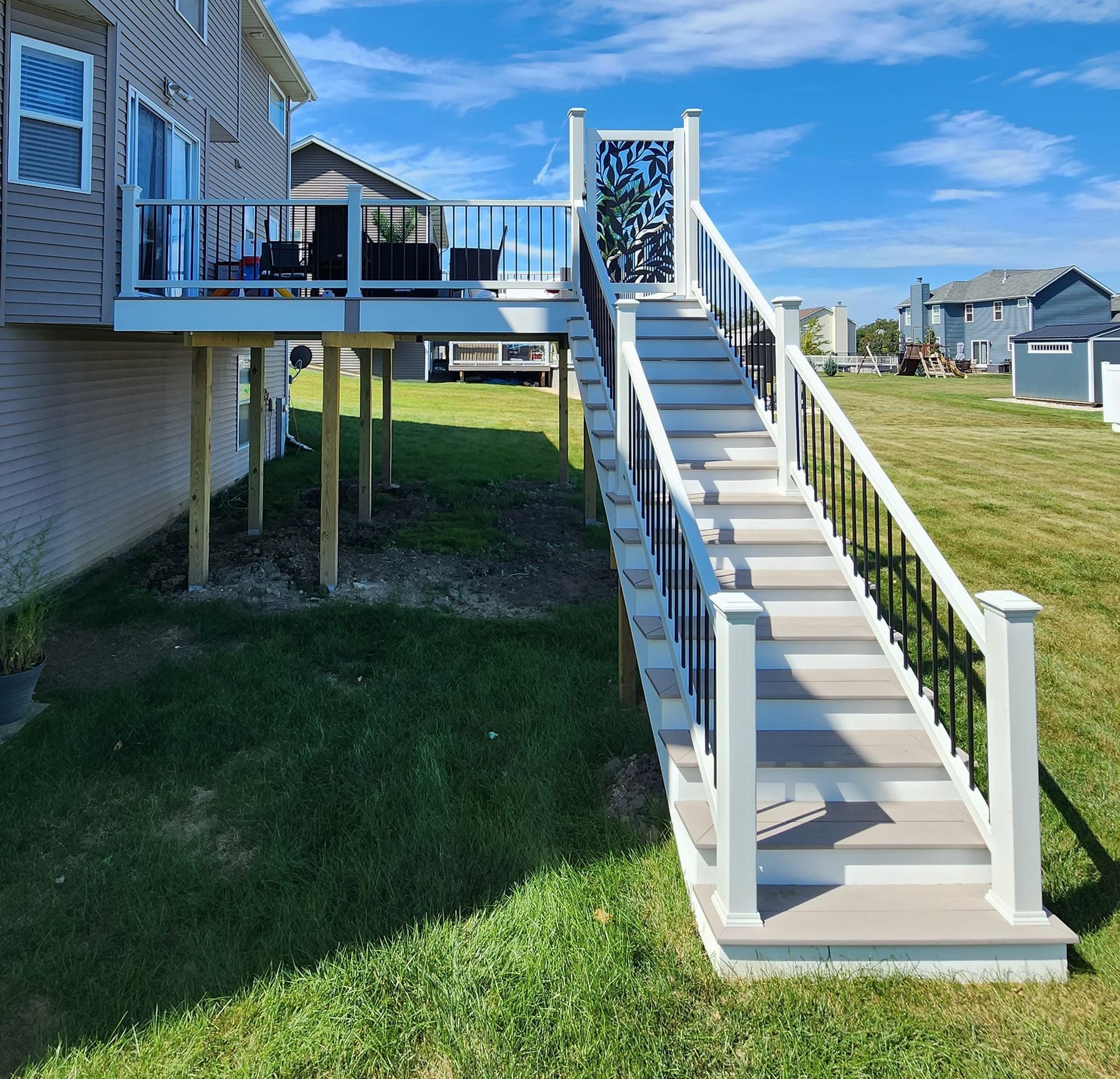A deck with stairs leading up to it and a house in the background