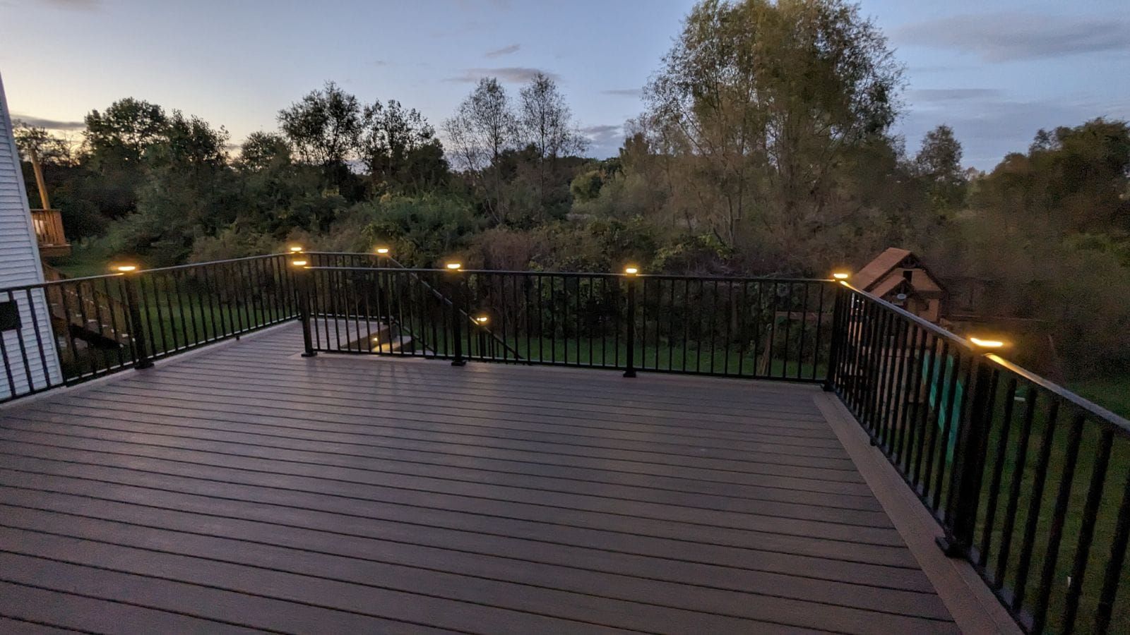 There is a deck with a railing and lights on it.
