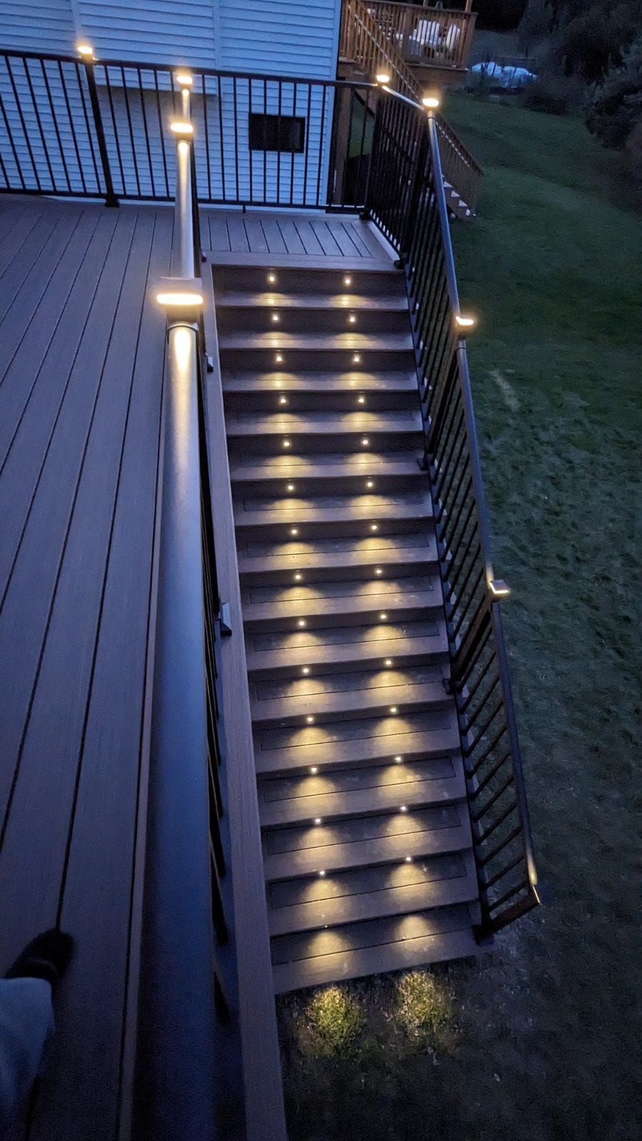 A deck with stairs that are lit up at night.