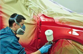 Man applying red paint to the body of a car