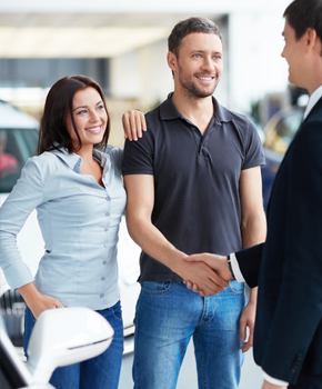 Happy couple shaking hands with the buyer of their old car