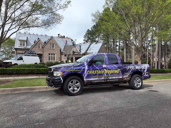 A purple, lightning-patterned Chastain Roofing pickup truck parked in front of a residential home undergoing roof repairs.