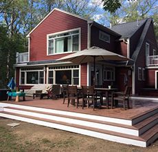 A large red house with a large deck and umbrella.
