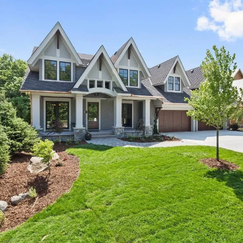 A two-story house with gray siding, gabled roof, and a well-manicured lawn.