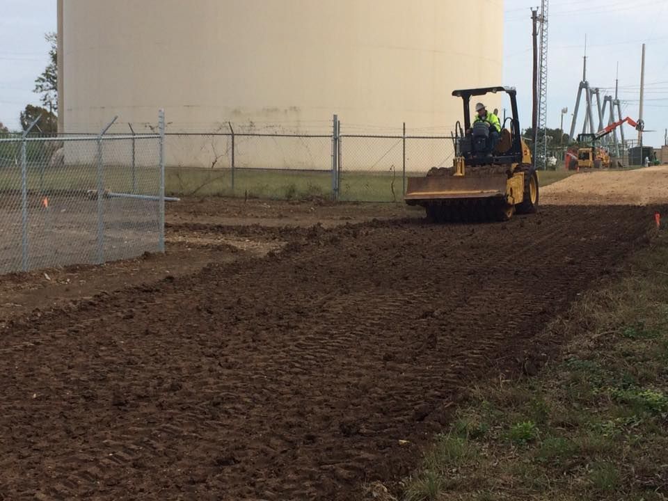 A man is driving a bulldozer on a dirt road.