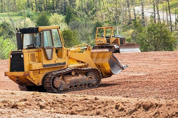 A bulldozer is sitting in the middle of a dirt field.