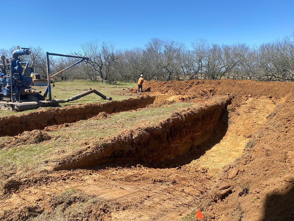 A man is digging a hole in the dirt in a field.