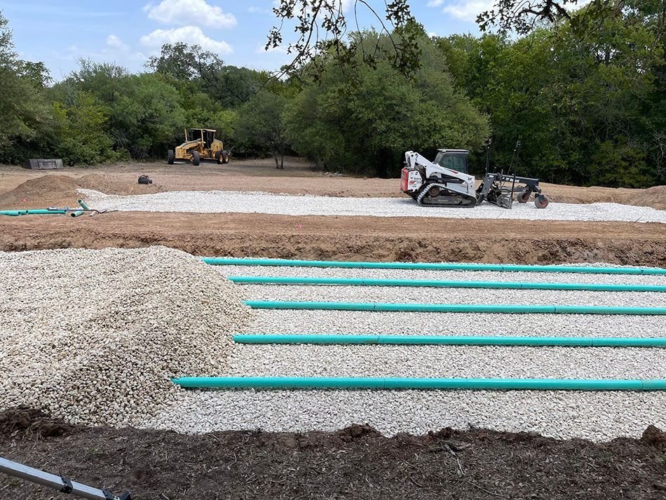 A bulldozer is working on a septic system in a field.