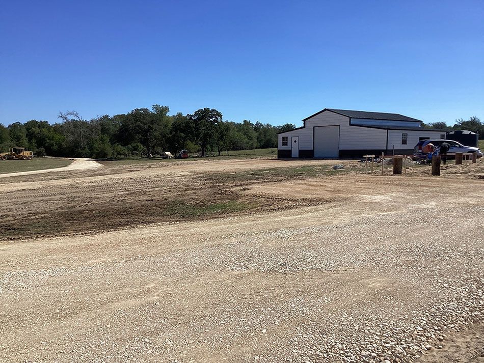A large white building is in the middle of a dirt field.