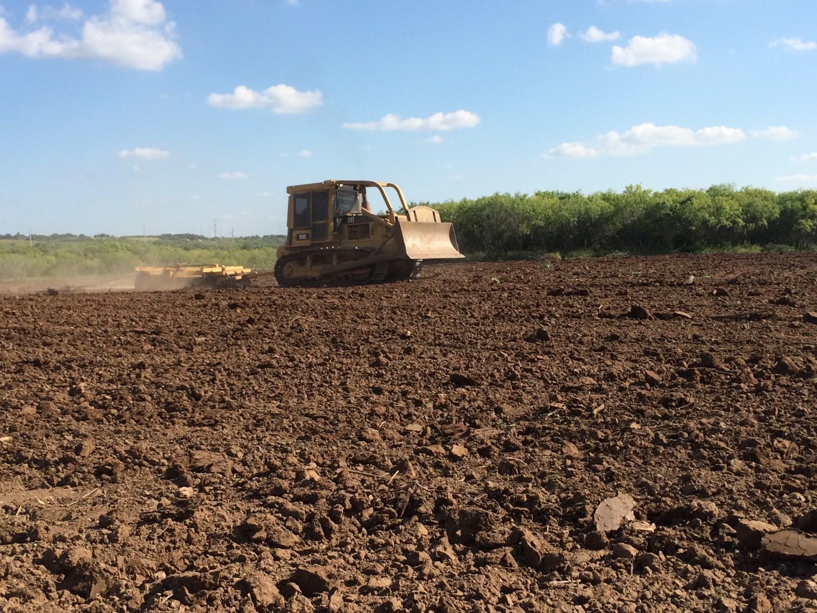 A bulldozer is plowing a field of dirt.