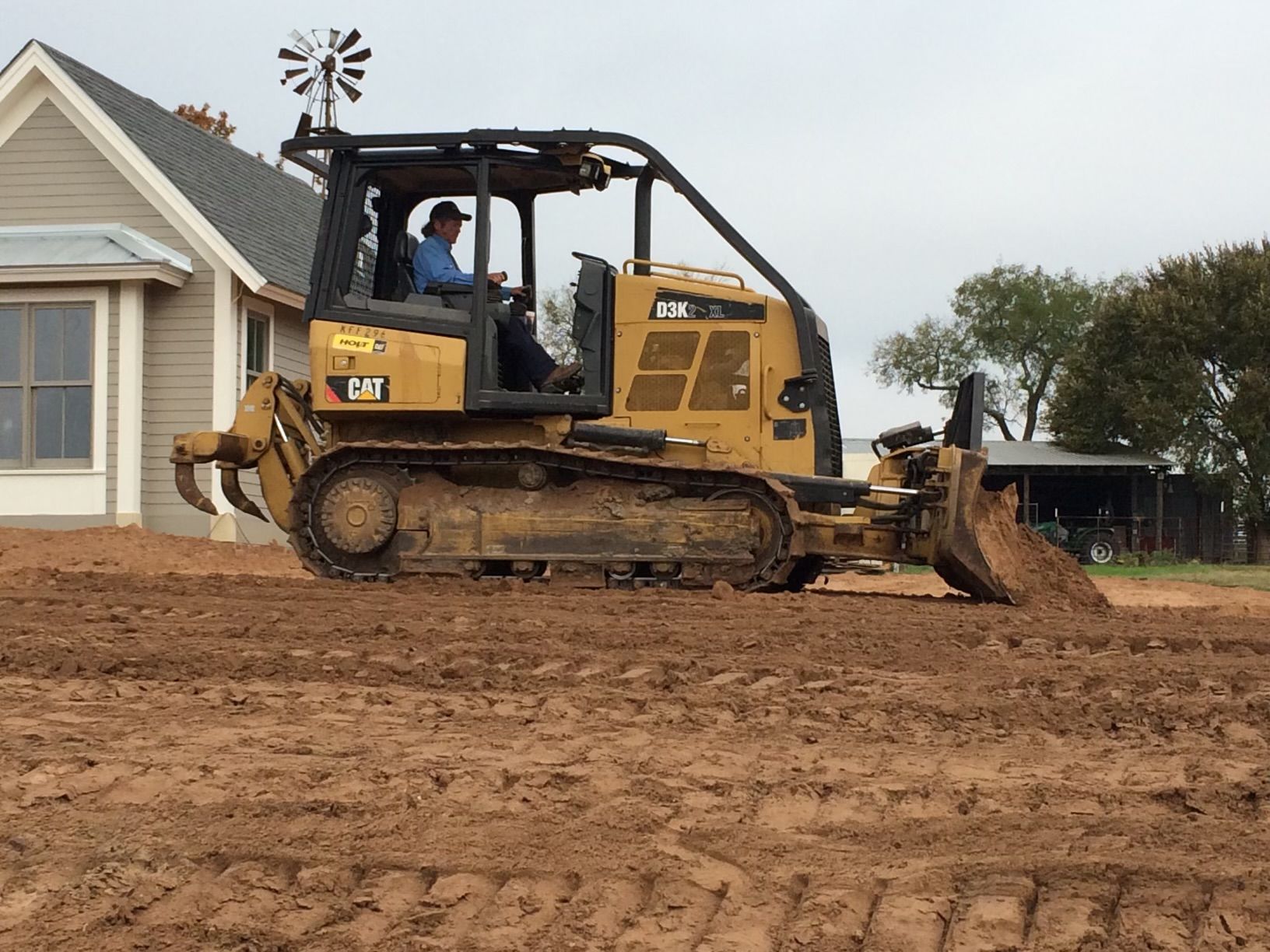A bulldozer is moving dirt in front of a house.