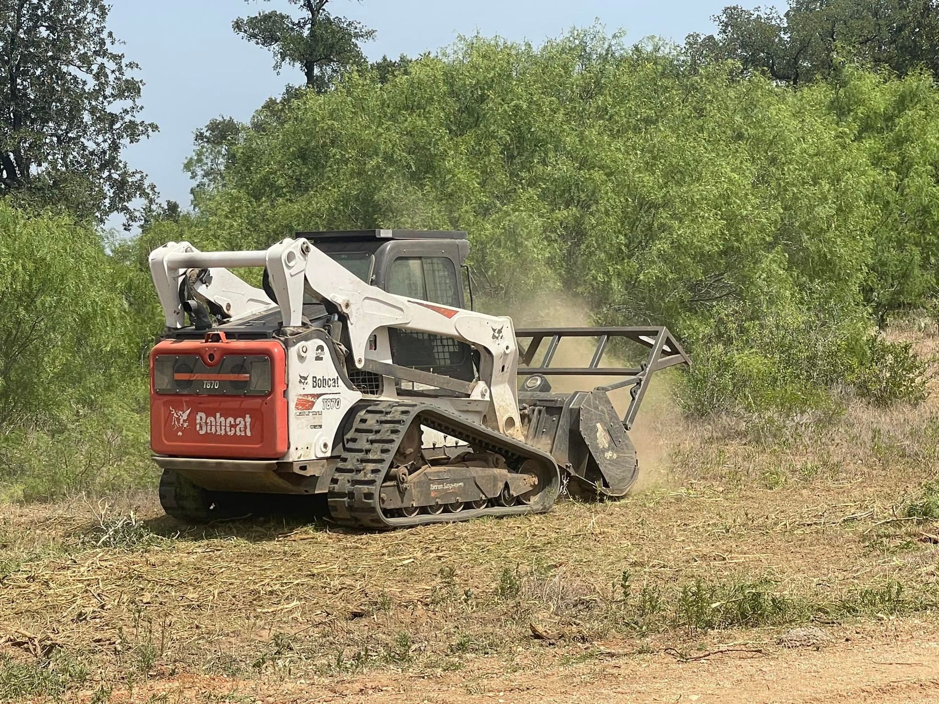A bulldozer is cutting grass in a field.