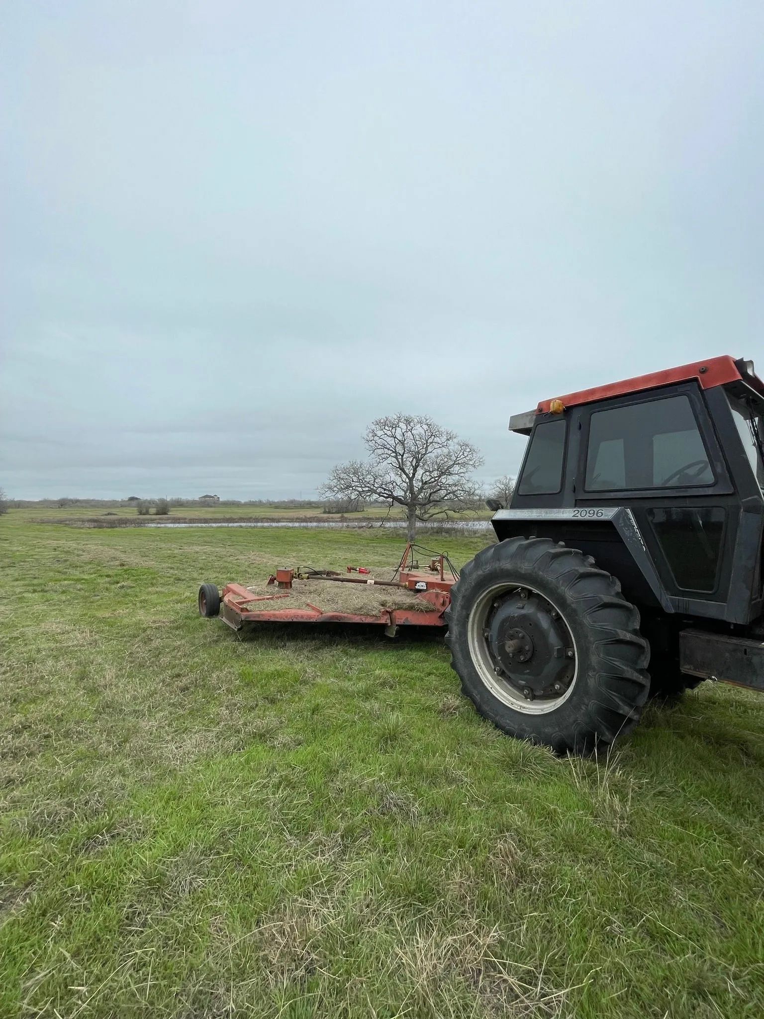 A tractor is parked in a grassy field with a mower attached to it.