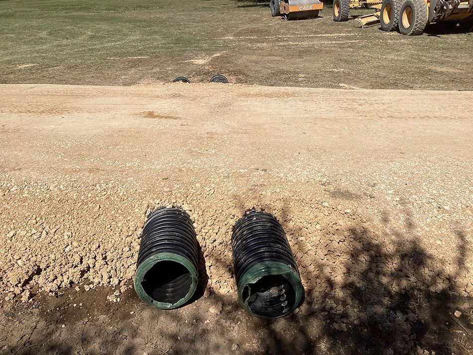 A couple of pipes are sitting in the dirt in a field.