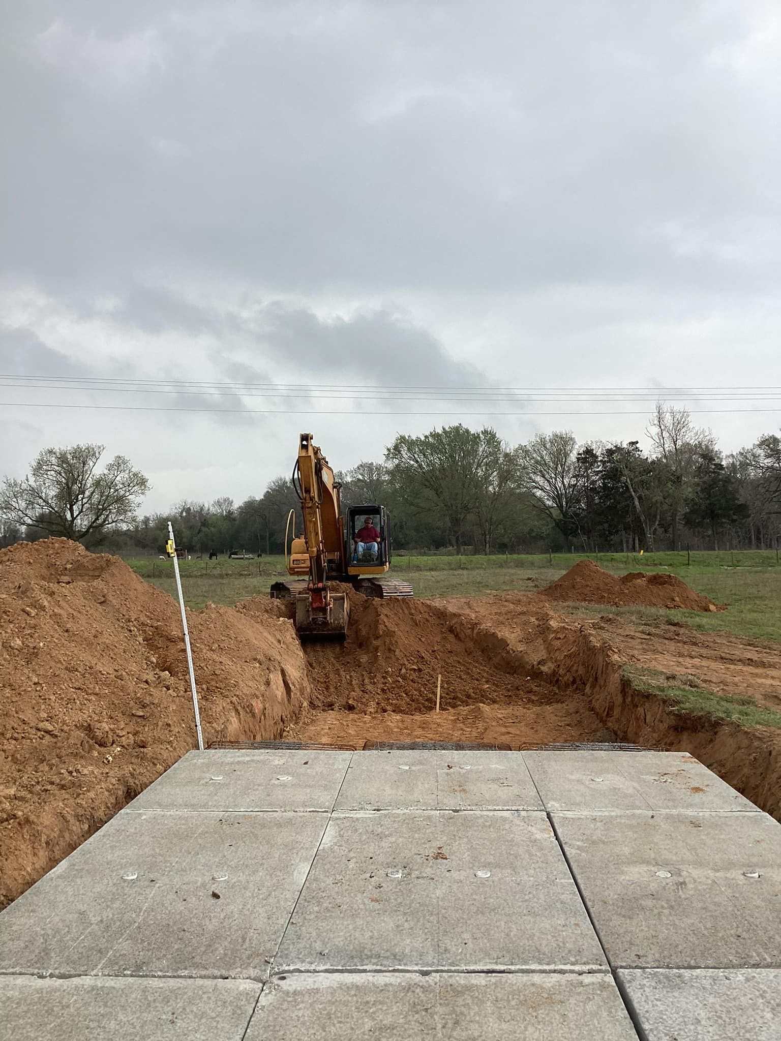 An excavator is digging a hole in the dirt in a field.