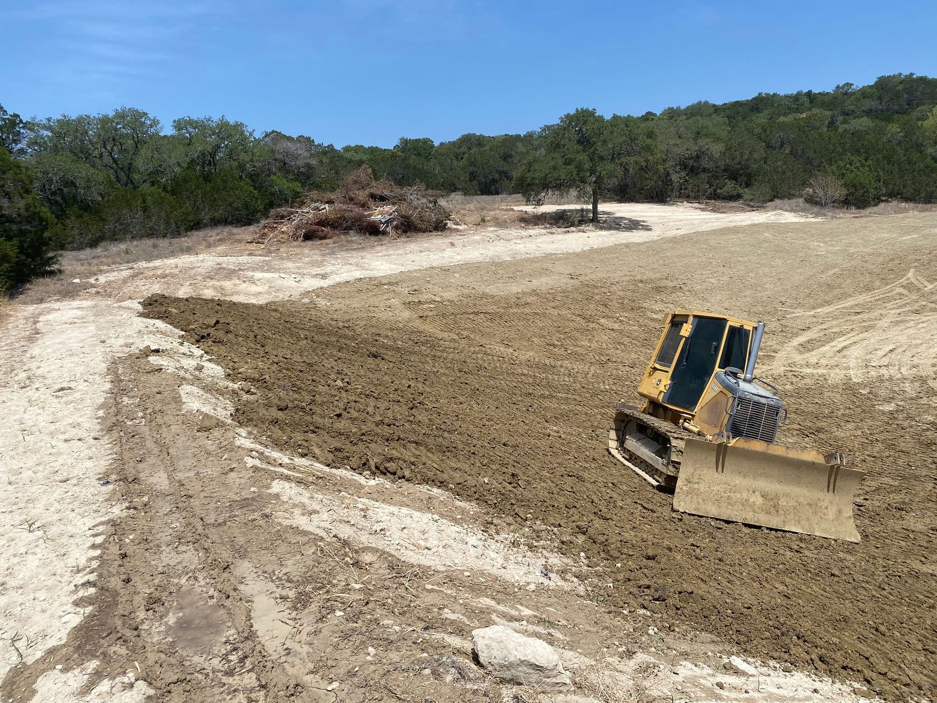 A bulldozer is sitting in the middle of a dirt field.