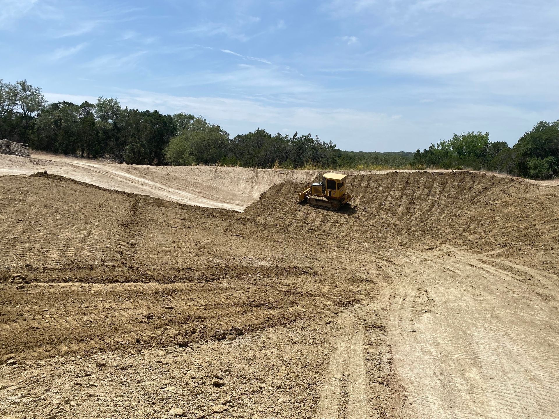 A bulldozer is driving through a dirt field.