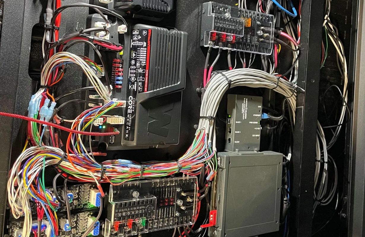 A panel filled with a complex arrangement of wires, circuit boards, and electronic components, likely in a vehicle or machine.