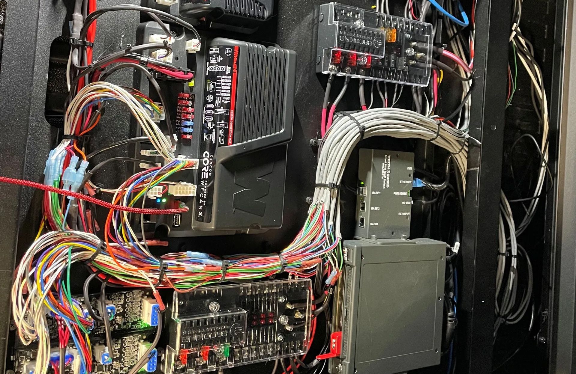 A panel filled with a complex arrangement of wires, circuit boards, and electronic components, likely in a vehicle or machine.