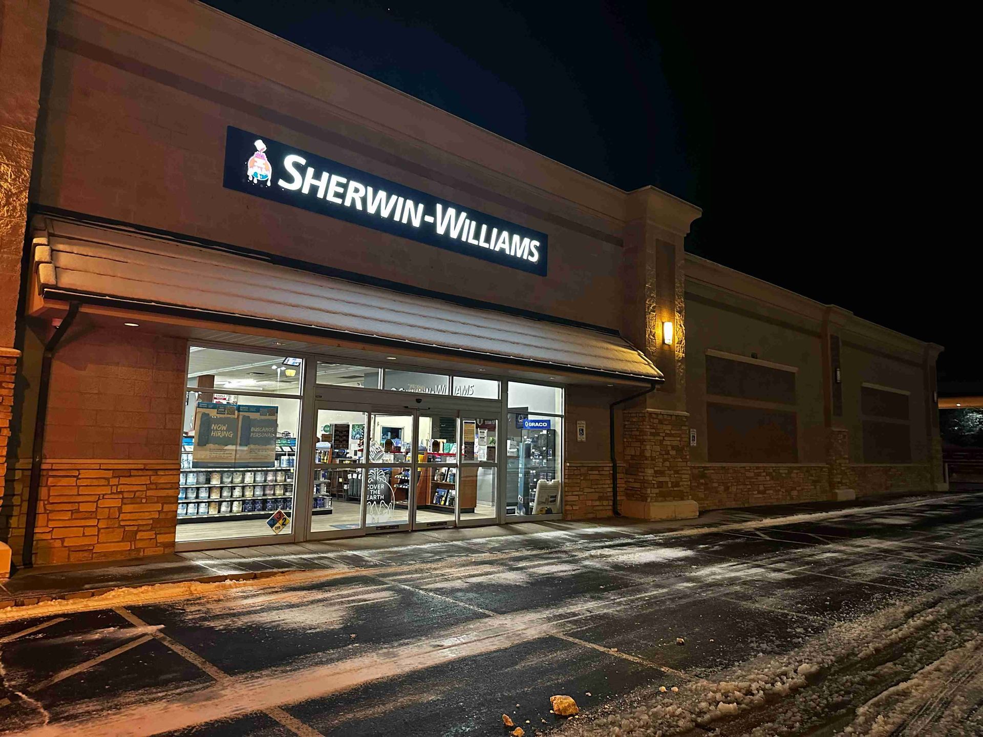 Sherwin-Williams store at night with illuminated sign and snowy parking lot