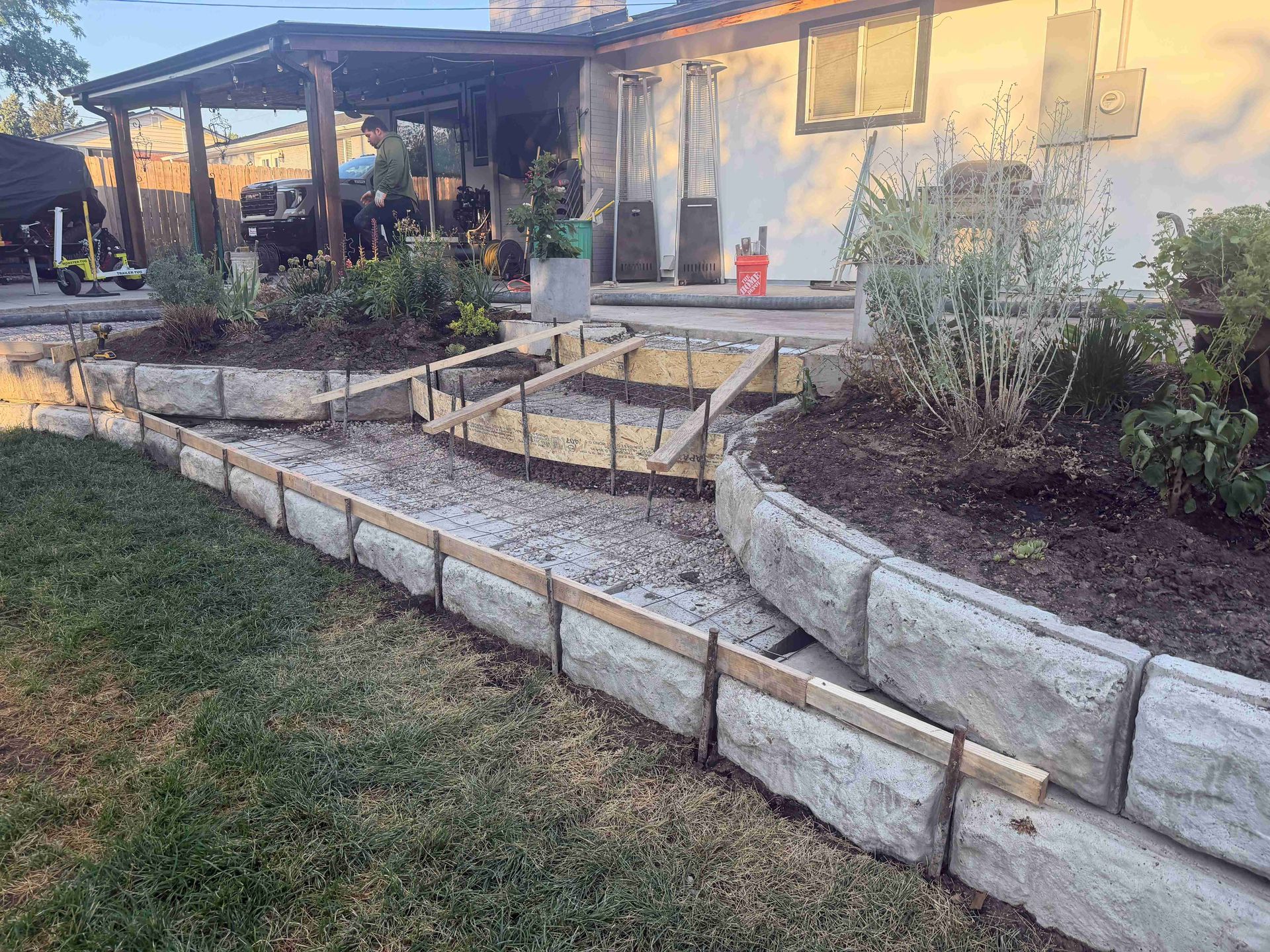 Terraced stone garden beds and gravel path beside a house patio at sunset