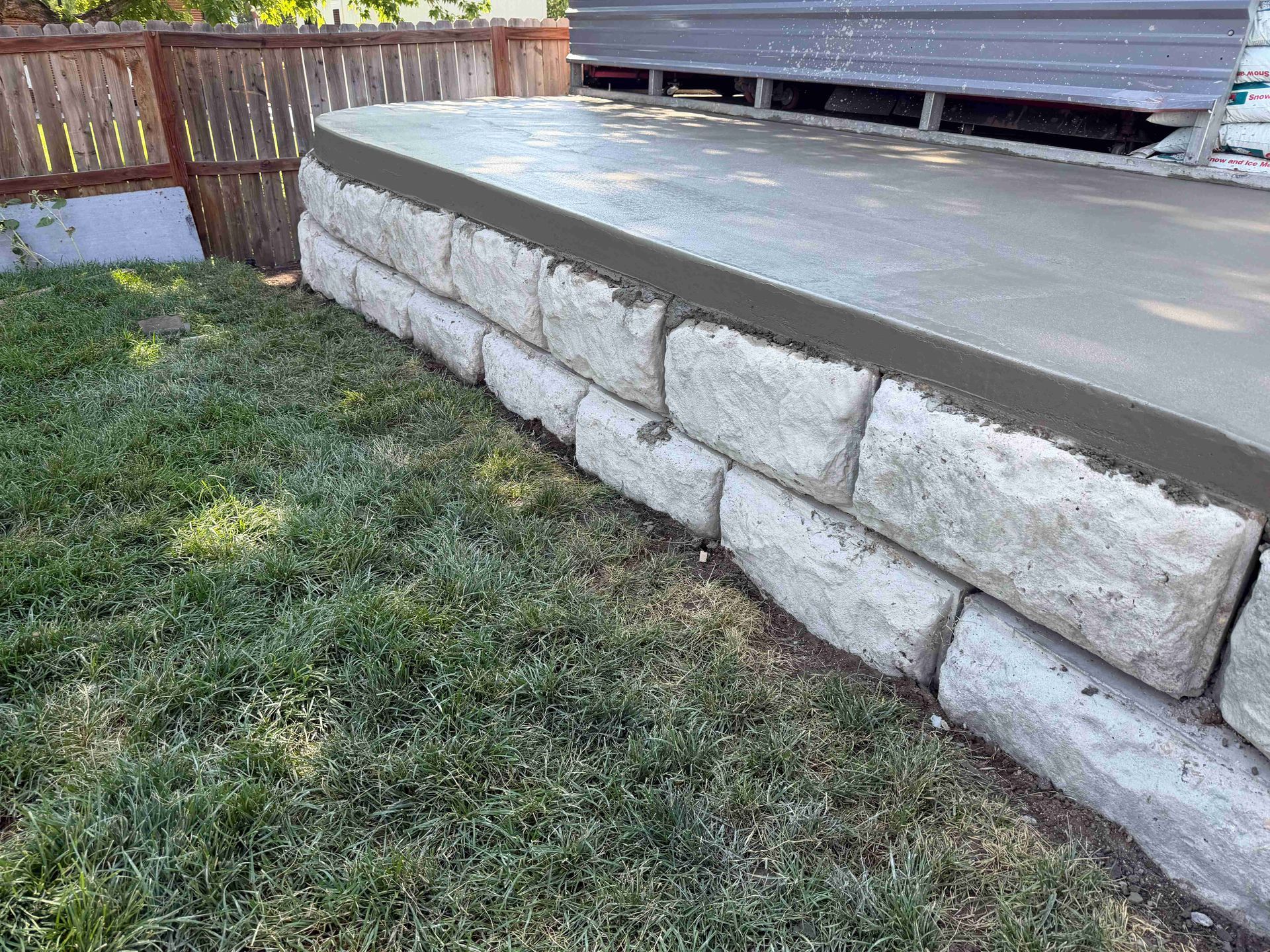 Stone retaining wall beside a raised deck and grassy yard