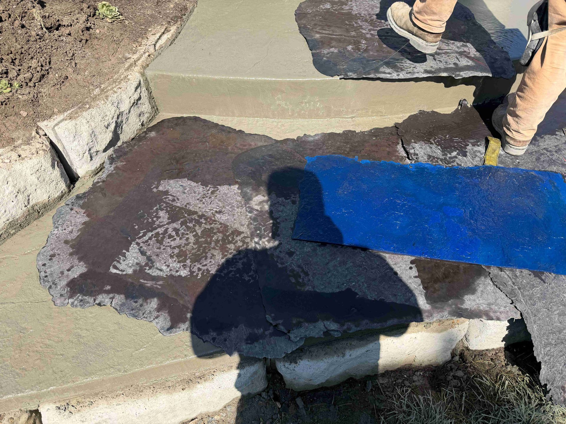 A person stepping over cracked concrete beside a bright blue mat outdoors.