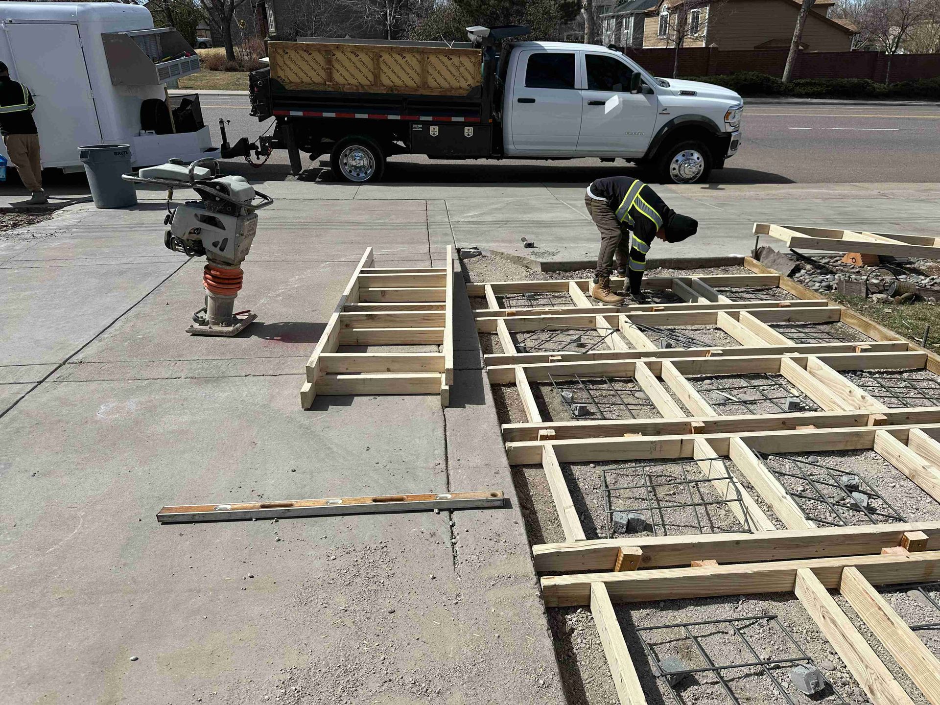 Workers building a wooden frame on a concrete slab beside a white utility truck