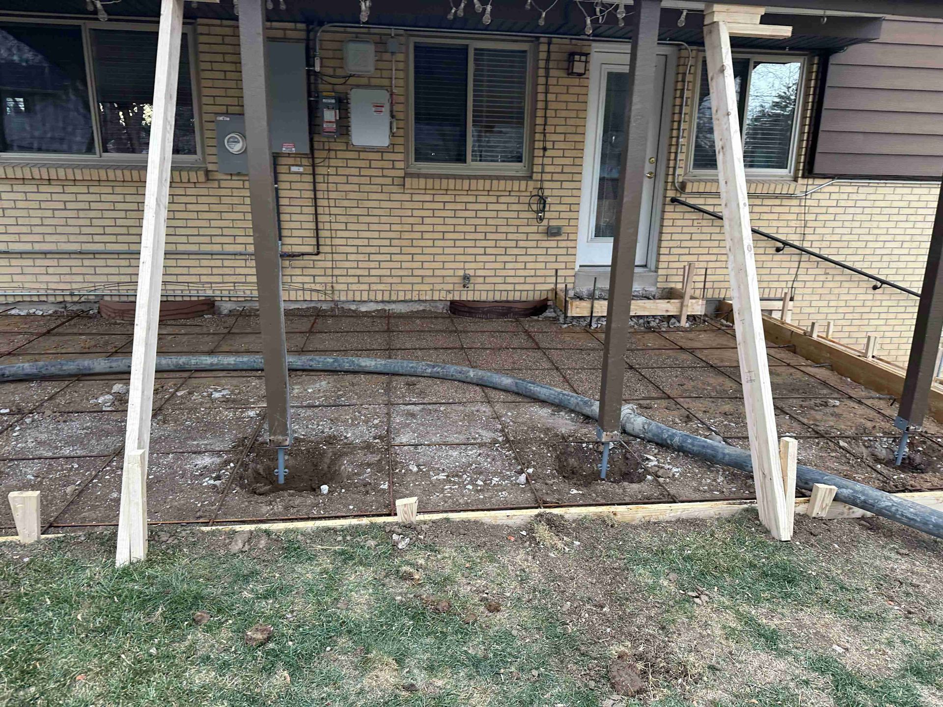 Porch of a damaged house with charred siding, cracked brick, and debris on the ground