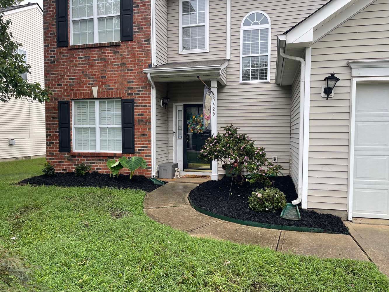 The front of a house with a brick building and a white garage door.