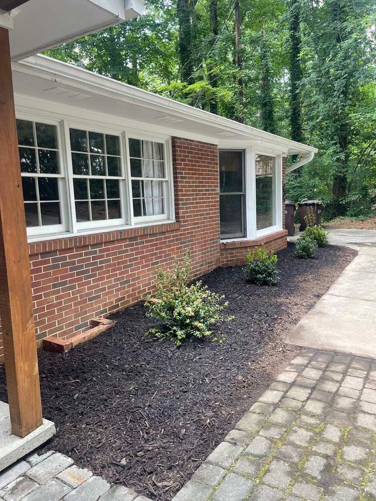 A brick house with a lot of windows and a patio in front of it.