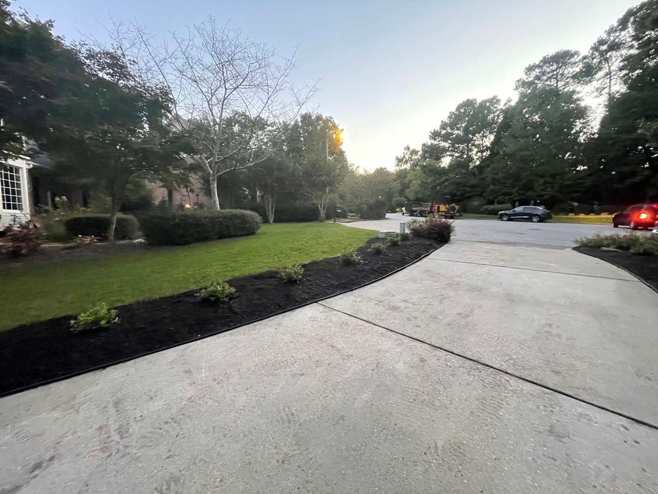 A concrete driveway leading to a house in a residential neighborhood.