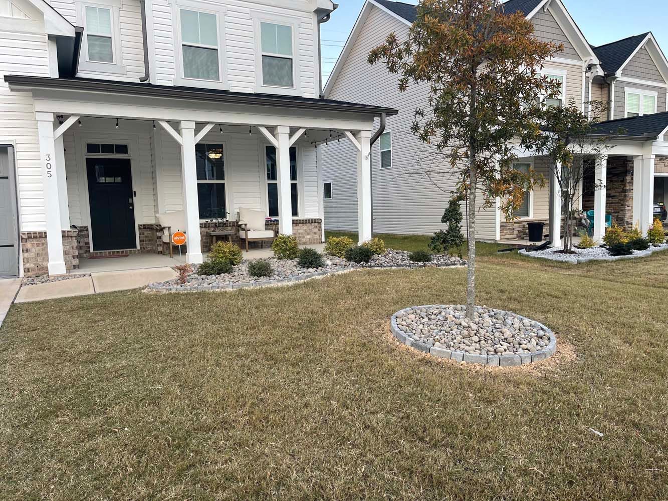 A house with a porch and a large lawn in front of it.